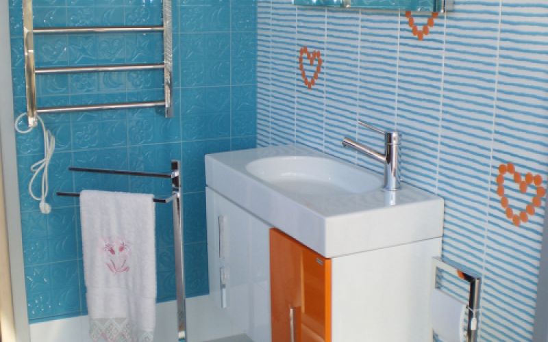 Baño completo en exposición con azulejos azules y corazones